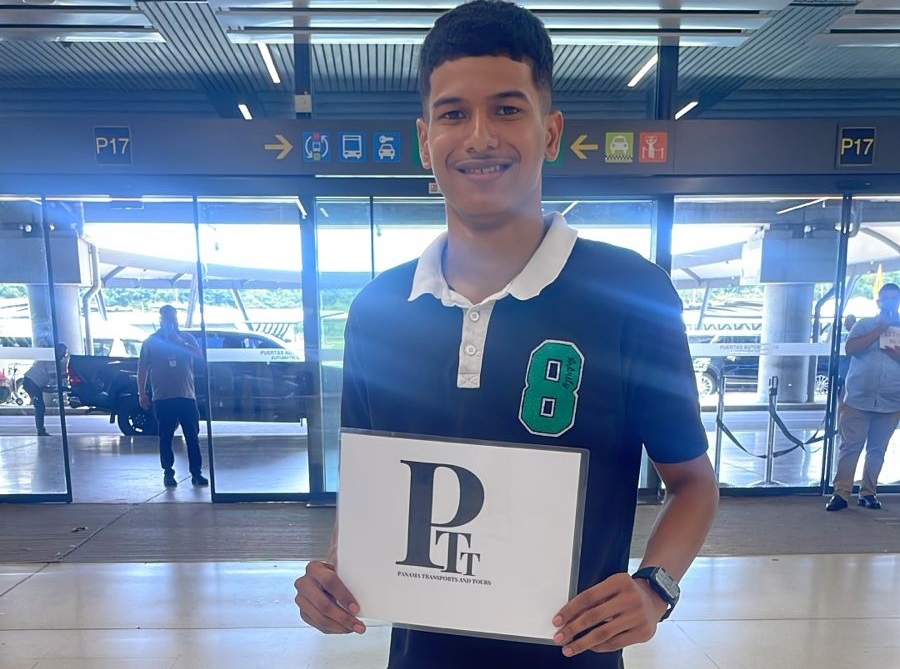 Conductor profesional esperando a los pasajeros con cartel de bienvenida en el Aeropuerto Internacional de Tocumen